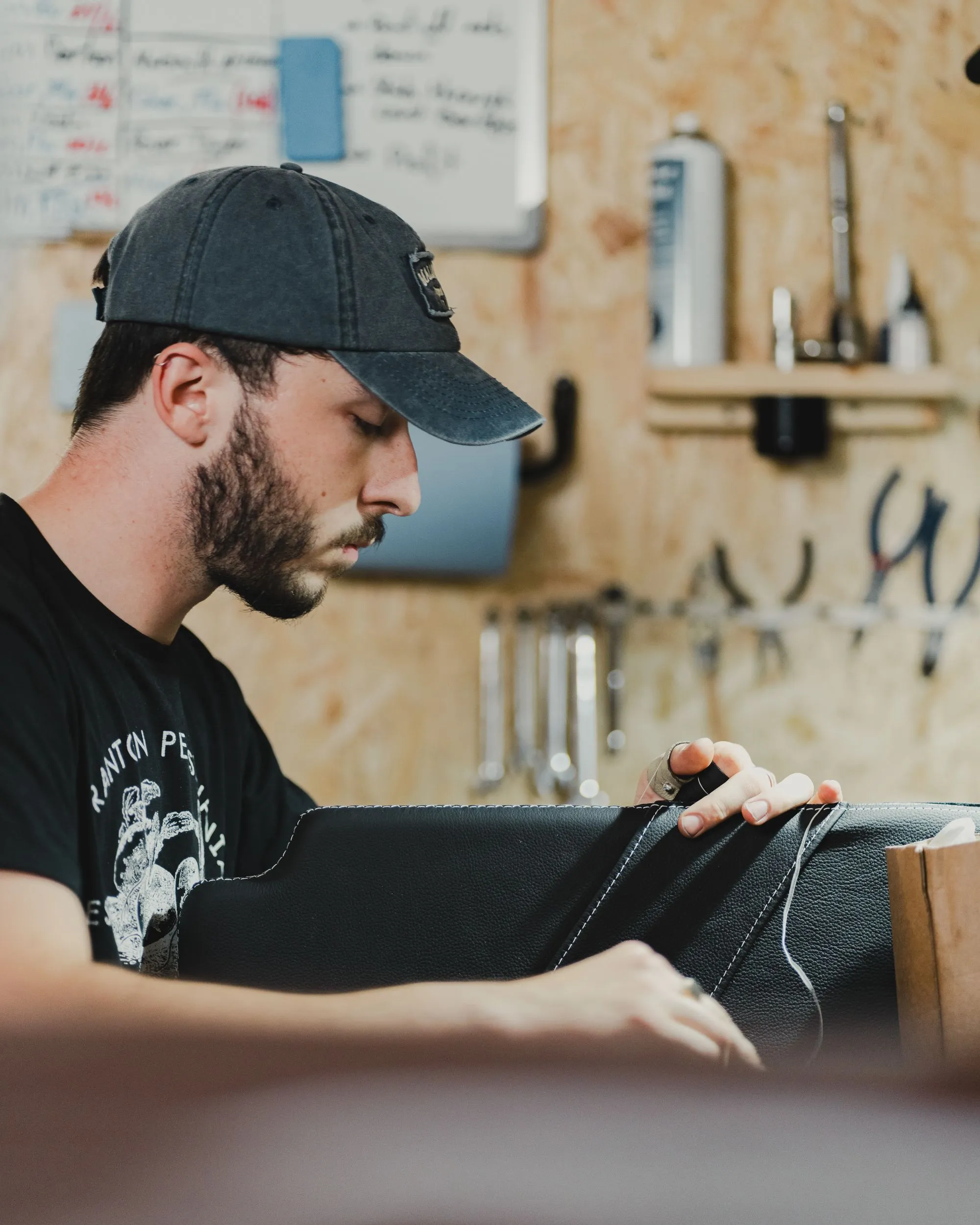 Un artisan coud une pièce de cuir dans son atelier