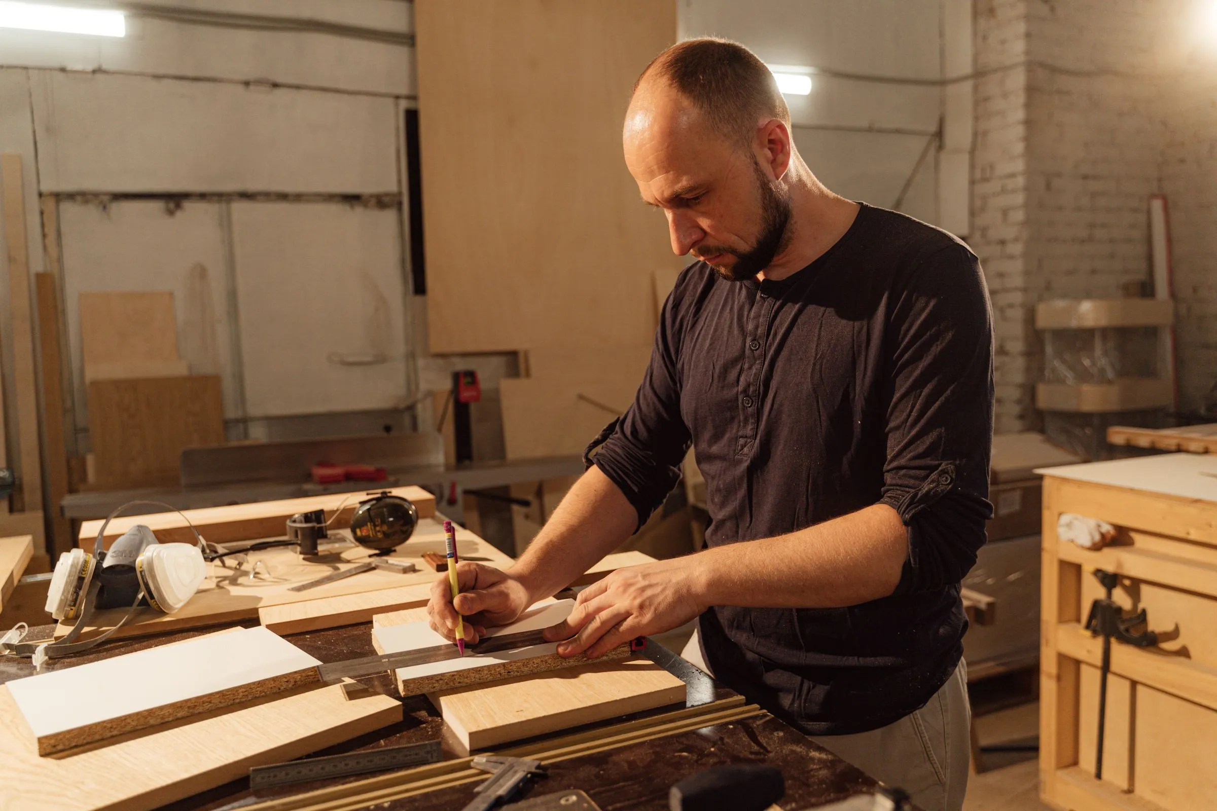 Un artisan mesure une planche de bois dans son atelier