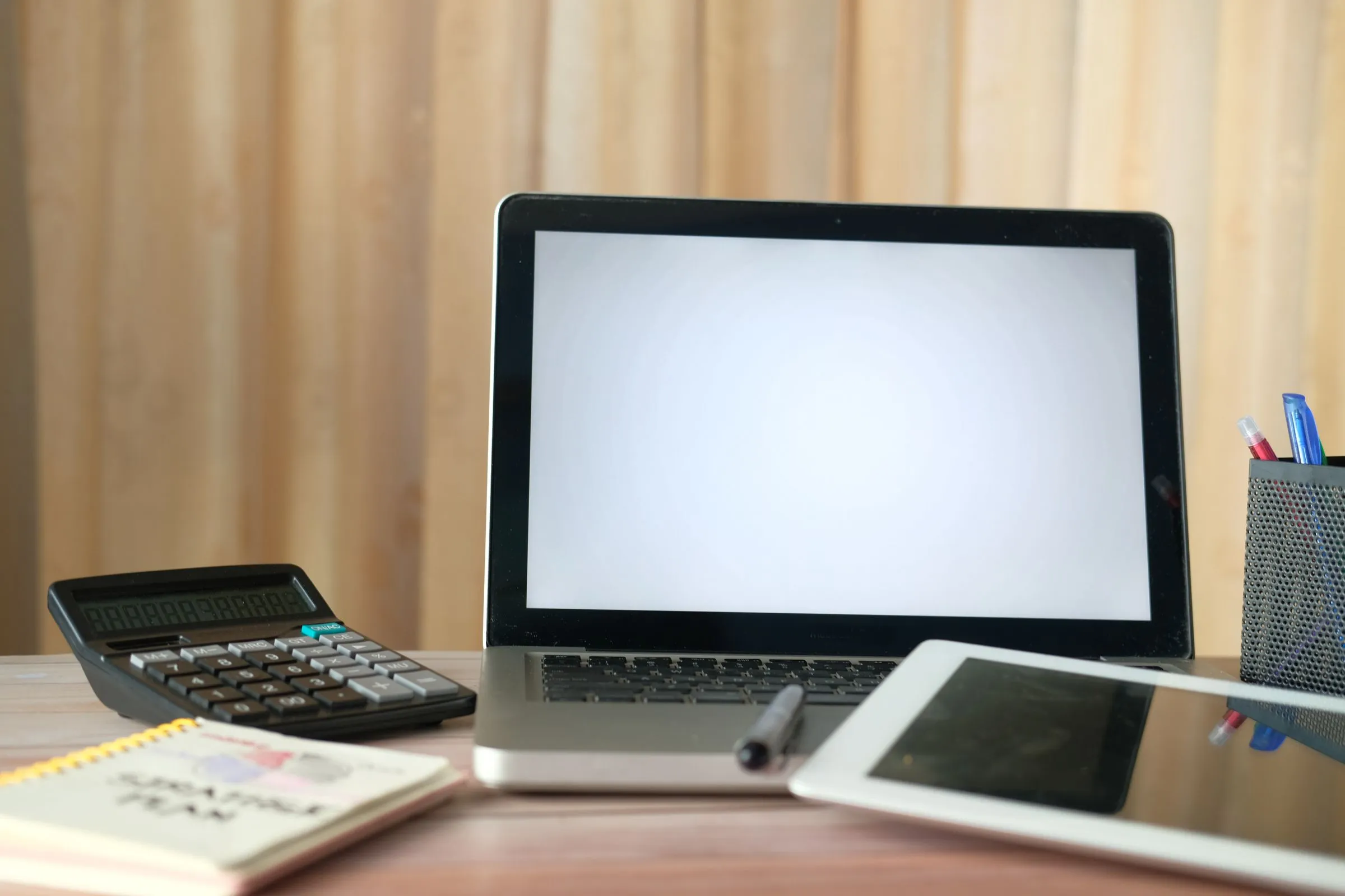 Un ordinateur portable, une calculatrice et une tablette sur un bureau