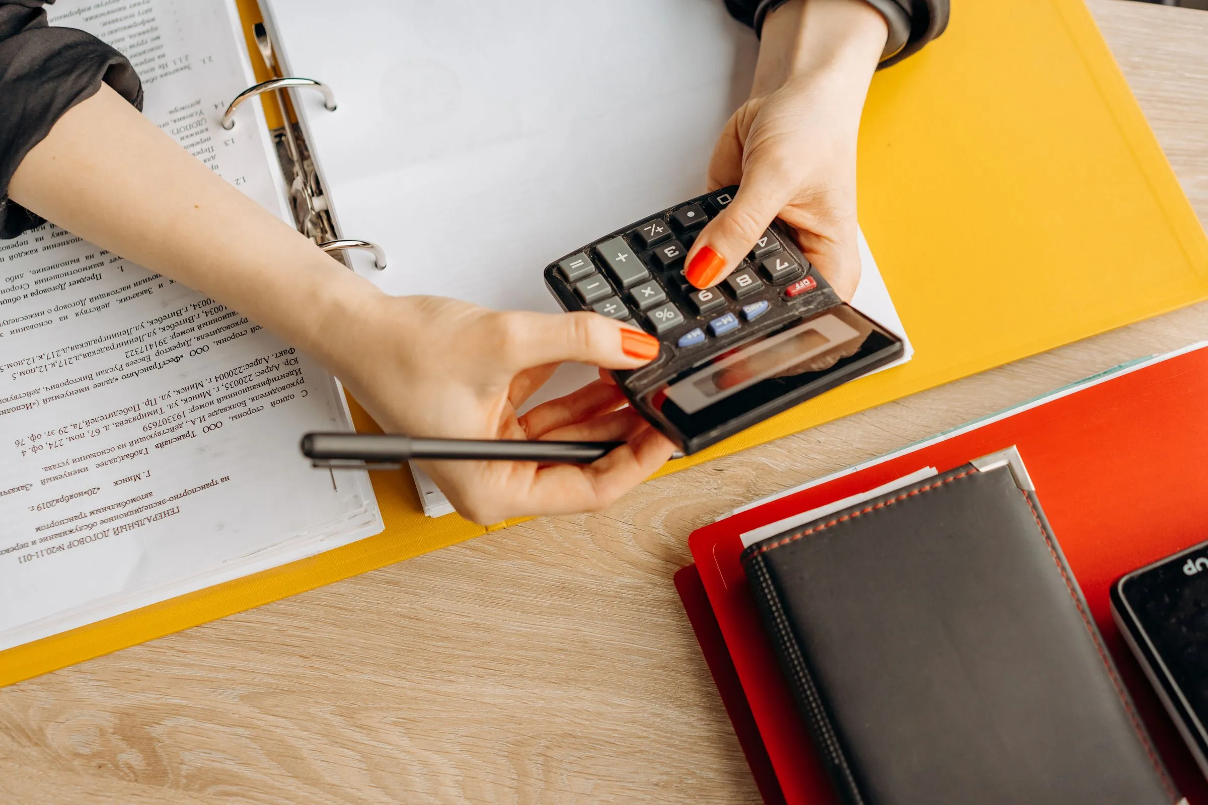 Mains sur une calculatrice au-dessus d'un classeur de documents